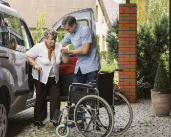 caregiver assisting the elderly woman getting out the car