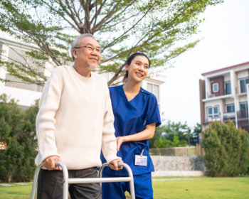 elderly man and caregiver walking outside