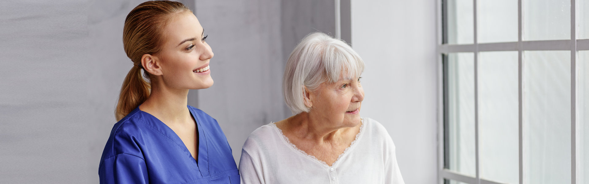 caregiver and elderly woman looking outside
