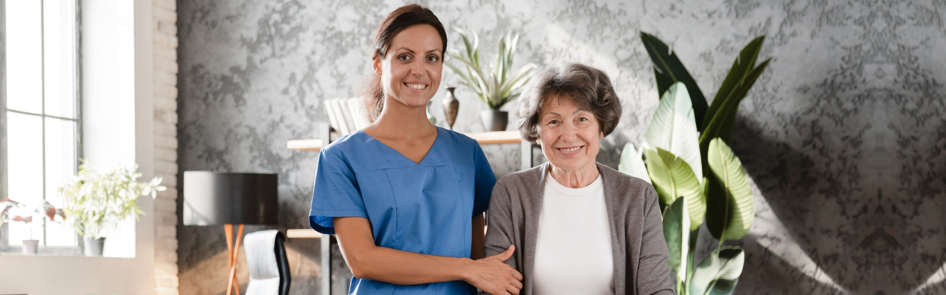 caregiver and elderly woman standing in the living room